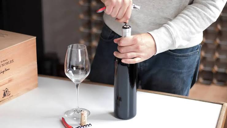 Hướng dẫn kỹ thuật rót rượu vang chuẩn Sommelier trên bàn tiệc Cắt lớp bọc kim loại dưới vòng gờ cổ chai và lau sạch miệng chai trước khi rót rượu vang.